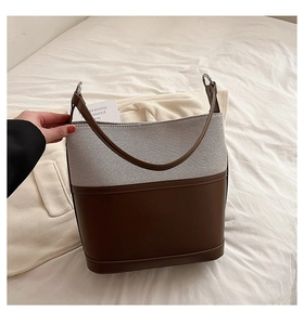 Detail view of large bucket bag with brown leather and canvas patchwork texture