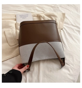 Detail view of brown leather and tweed bucket bag with adjustable shoulder strap