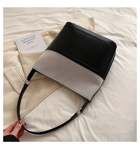 Close-up of contrast bucket bag with black leather and grey canvas on white bedding
