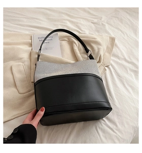 Detail of two-tone bucket bag with white woven texture and black leather base
