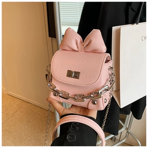Detail of pink mini box bag with oversized bow and silver chain strap for women