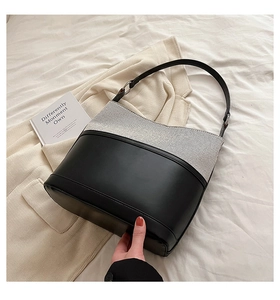 Detailed shot of grey fabric and black faux leather patchwork hobo bag with silver hardware