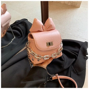 Detail of pink bow mini crossbody bag featuring metallic chain and wrinkled PU leather