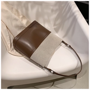 Detail of minimalist bucket bag showing brown leather and beige canvas texture contrast