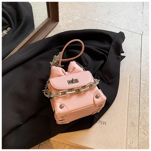 Detailed macro of pink box bag with metallic texture, bow detail and metal chain strap