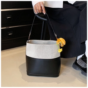 Detail of canvas and leather bucket bag featuring elegant contrast stitching and textures