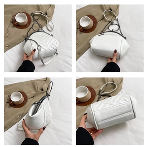 Detail view of white quilted shell bag with metallic ring handle and chain strap