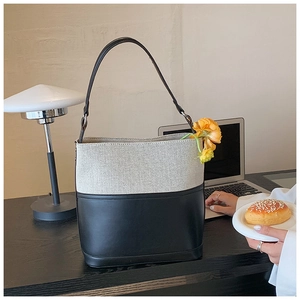 Detail of canvas and black leather bucket bag with flowers in a cozy home office setting