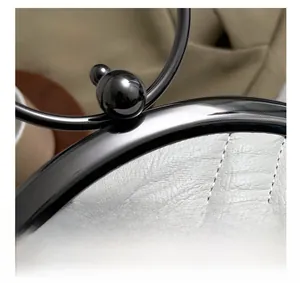 Macro shot of white quilted leather texture and round black metal lock on shell bag