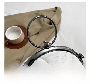 Detail of white quilted leather shell bag with round metal handle and clasp closure