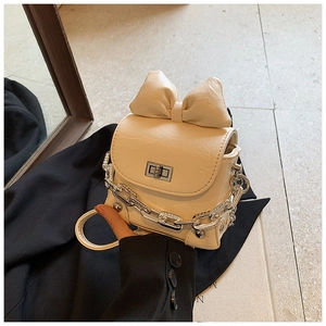 Close-up of cream mini bag with large bow decoration and silver chain strap details