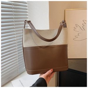Detail of beige canvas and brown leather patchwork tote bag on a minimalist background