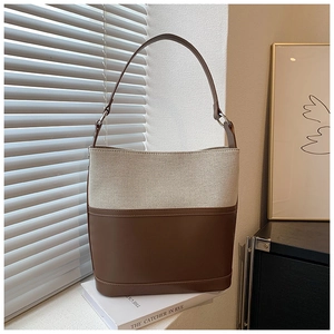 Detail of a minimalist bucket bag featuring ivory canvas and dark brown leather contrast