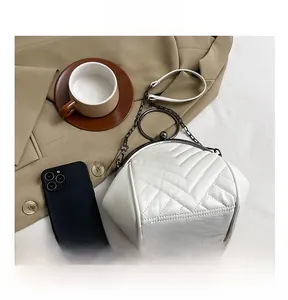 Detailed view of the white V-quilted shell bag with vintage metal clasp and chain strap