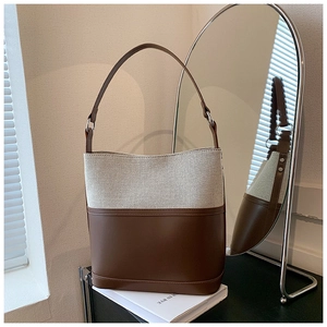 Chic two-tone canvas bucket bag with brown leather accents on a minimalist background