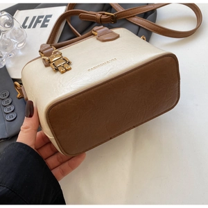 Détail d'un sac seau vintage en cuir beige et marron avec un pendentif robot métallique