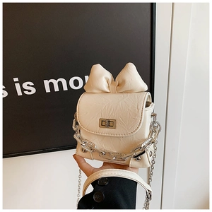 Detail of cream mini box bag featuring oversized bow and silver chain strap