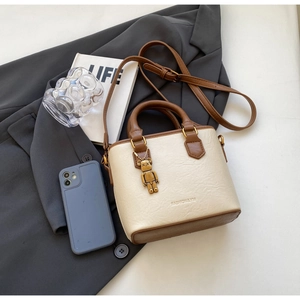 Détail du sac fourre-tout bicolore crème et marron avec breloque de mode sur accessoires
