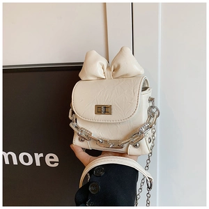 Detailed view of mini cream crossbody bag featuring a large leather bow and silver chain