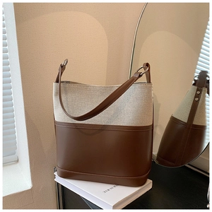 Detailed close-up of the canvas and leather stitching on the chic bucket handbag