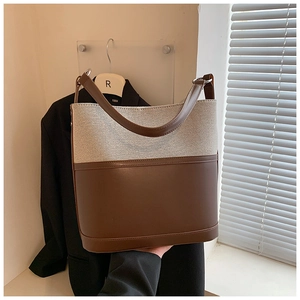 Detail of minimalist beige canvas and brown leather stitching on a large tote bag