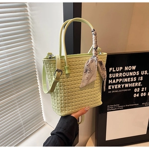 Macro view of woven light green leather bucket bag with silk scarf on the round handle