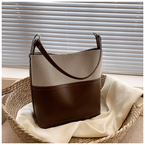 Detail of canvas and leather bucket bag with silver hardware in a woven basket