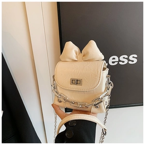 Detail of a mini cream-white bow box bag with silver chain and metallic square lock