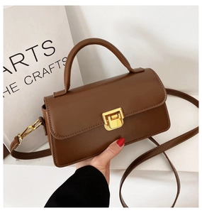 Dettaglio della borsa vintage marrone in pelle con fibbia quadrata dorata e manico