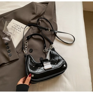 Detail of black patent leather crossbody bag with diamond quilting and silver hardware