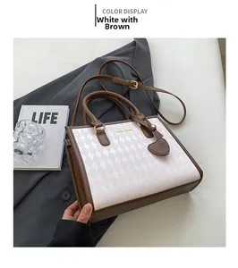 Detail of white quilted tote with coffee leather trim and gold heart pendant