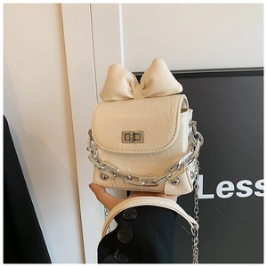 Close-up of beige pleated mini box bag featuring a large bow and silver chain strap