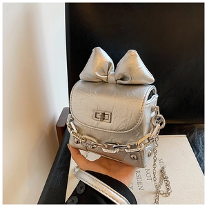 Detail of silver mini box bag featuring a metallic crinkled texture and large bow