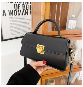 Dettaglio di una borsa nera vintage in pelle con chiusura a pressione in metallo dorato