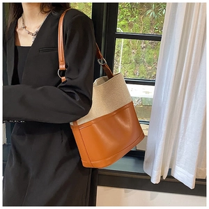 Detail view of contrast stitching on beige canvas and caramel leather bucket bag texture