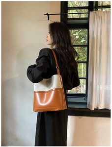 Detail of two-tone bucket bag with brown leather and beige canvas on shoulder