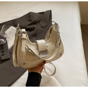 Close-up of cream crescent bag featuring diagonal quilting, silver studs and chain strap