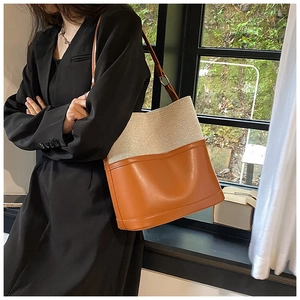 Detail of canvas and brown leather stitching on a stylish bucket bag with shoulder strap
