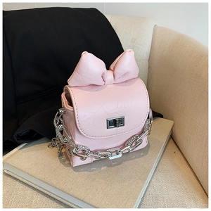 Detailed view of a pink mini box bag with oversized bow and rhinestone chain