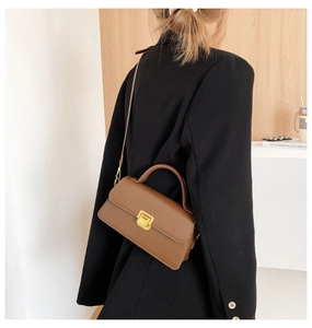 Borsa a tracolla retrò marrone con fibbia dorata abbinata a un blazer nero