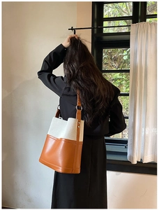 Detail of cream canvas and brown leather bucket bag shown on model in natural light