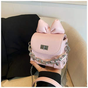 Close-up of a pink mini crossbody bag featuring a large bow and silver chain strap