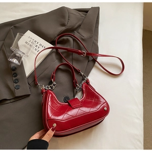 Detail of red quilted faux leather baguette bag with silver chain and shoulder strap