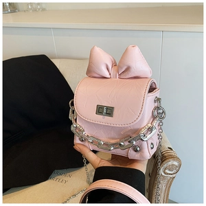 Detailed view of pink mini crossbody box bag with large bow and silver chain strap