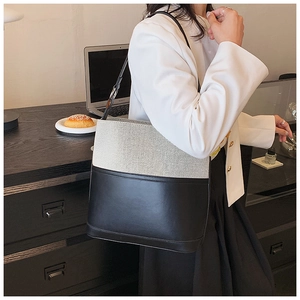 Detail of minimalist beige canvas and black leather bucket bag with silver hardware