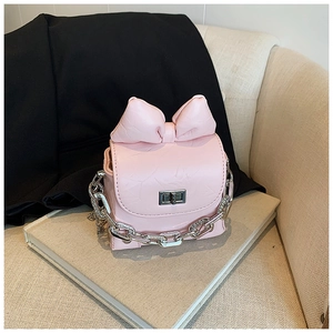 Detail of pink mini bow bag featuring PU leather texture and chunky silver chain strap