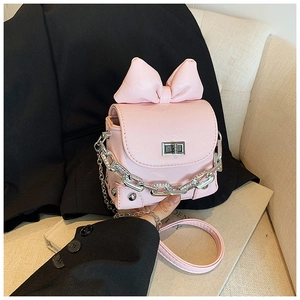Detail of pink mini box bag with large bow, silver chain, and metallic turn-lock closure