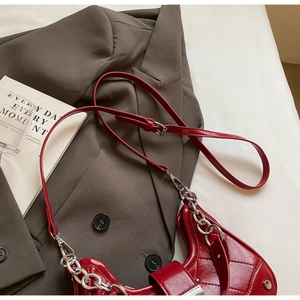 Detail of red quilted shoulder bag with silver chain and glossy finish