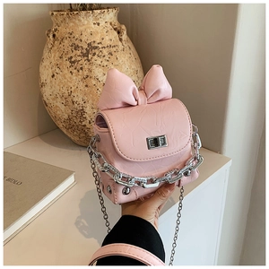 Detail of pink bow handbag with pleated texture, silver chain, and metal turn-lock closure