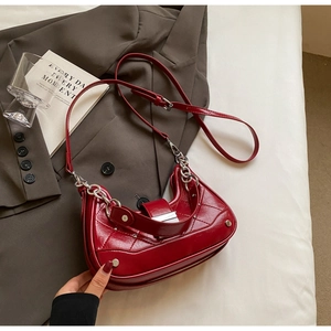 Detail of dark red quilted leather dumpling bag with silver chain and rivet accents